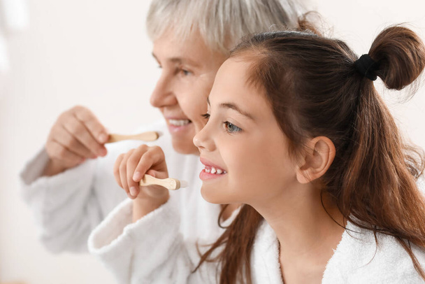 Niña y su abuela cepillándose los dientes en el baño, primer plano - Foto, imagen