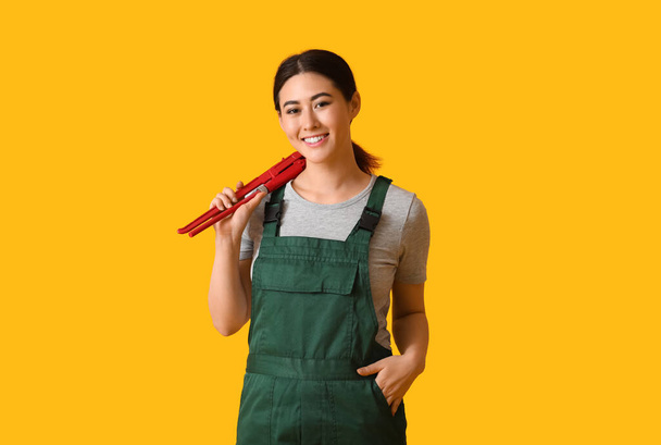 Asiatique plombier femelle avec clé à pipe sur fond jaune - Photo, image