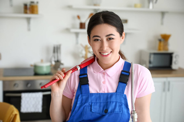 Asiatique femelle plombier avec tuyau clé dans la cuisine - Photo, image