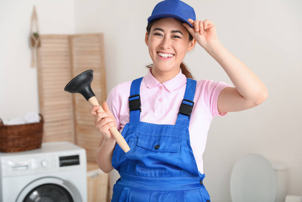 Asian female plumber with plunger in bathroom - Photo, Image