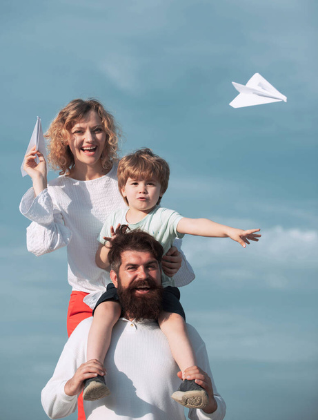Garden party in America. Dad mom and son playing together. Family dreams of traveling. Father mother and son in the park. Mother father and son. Cute little boy is holding paper airplane - Fotó, kép