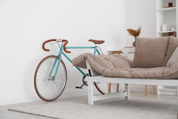 Modern bicycle near light wall in living room - Фото, изображение