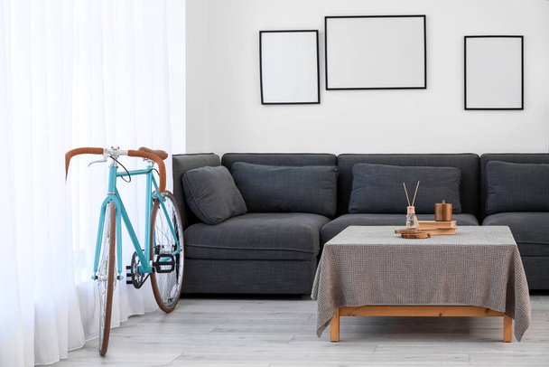 Interior of modern living room with bicycle, black sofa and blank frames - Photo, Image