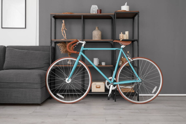 Современный велосипед возле полки в гостиной - Фото, изображение