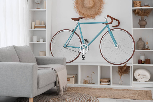 Интерьер современной гостиной с велосипедом, полками и диваном - Фото, изображение