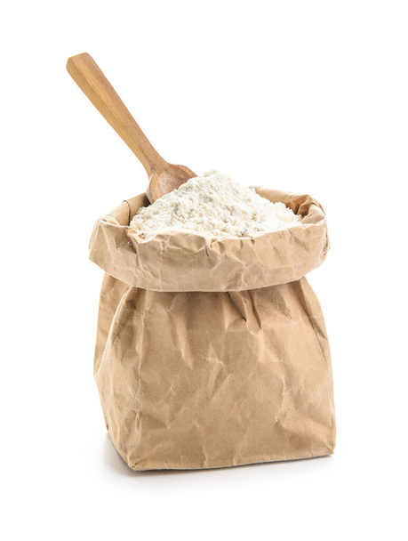 Bolsa de papel con harina de trigo y cucharada sobre fondo blanco - Foto, Imagen