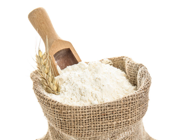 Saco con espigas de trigo, harina y cuchara sobre fondo blanco, primer plano - Foto, Imagen