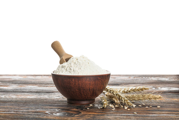 Bowl with flour, scoop and wheat ears on wooden table against white background - Photo, Image