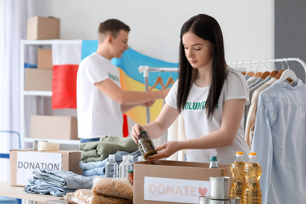 Voluntario polaco poniendo productos enlatados en la caja de donación para Ucrania en el centro - Foto, imagen