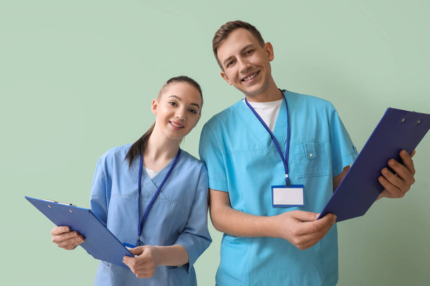 Medical assistants with clipboards on green background - Zdjęcie, obraz