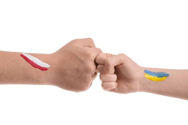 Добровольці з намальованими прапорами України та Польщі, які б "ють кулаками на білому тлі. - Фото, зображення