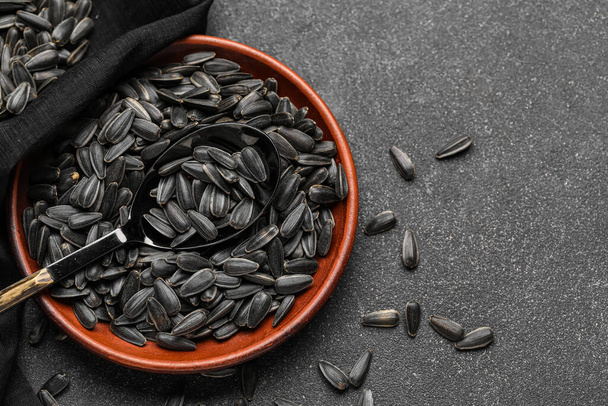 Cuenco, cuchara y servilleta con semillas de girasol negro sobre fondo oscuro - Foto, imagen