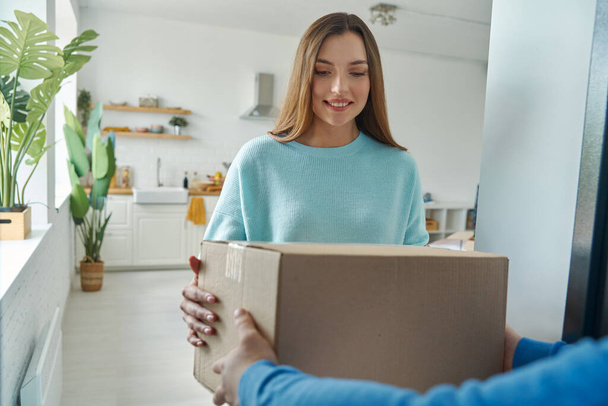 Beautiful young woman accepting box from delivery man at home - Fotoğraf, Görsel