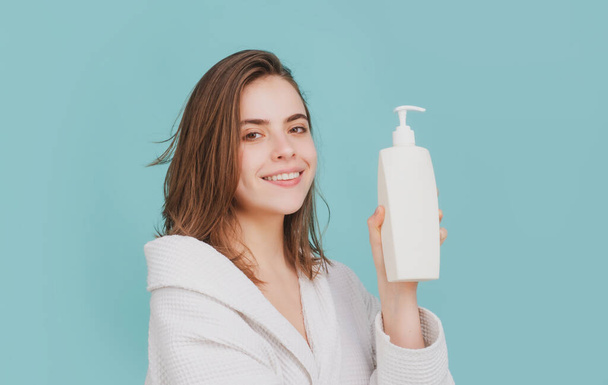 A beautiful young girl in the studio with wet hair. Beauty haircare cosmetics. Woman hold bottle shampoo and conditioner. Balm bottle - Foto, immagini
