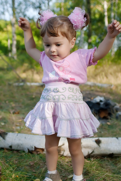 Girl with pink bows trying to jump - Foto, Imagen