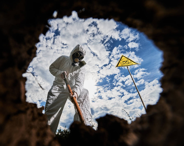 Kilátás a belső gödörből férfi tudós védő kopás és gázálarc dolgozik sérült talaj csinál kutatást radioaktív területen. Ökológus overálban ásni flóra alatt biológiai kísérlet. - Fotó, kép