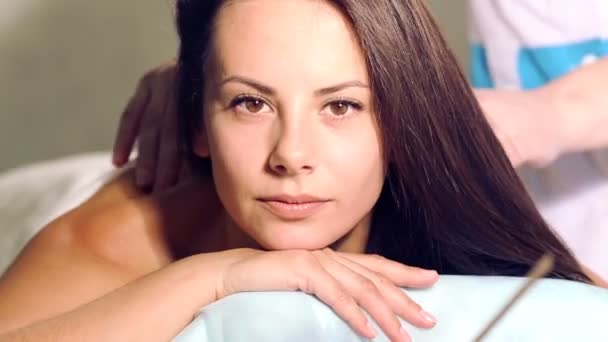 The young beautiful girl has a rest during the massage.Portrait of a young girl in the relaxation center.Girl face close-up to a massage. - Materiał filmowy, wideo
