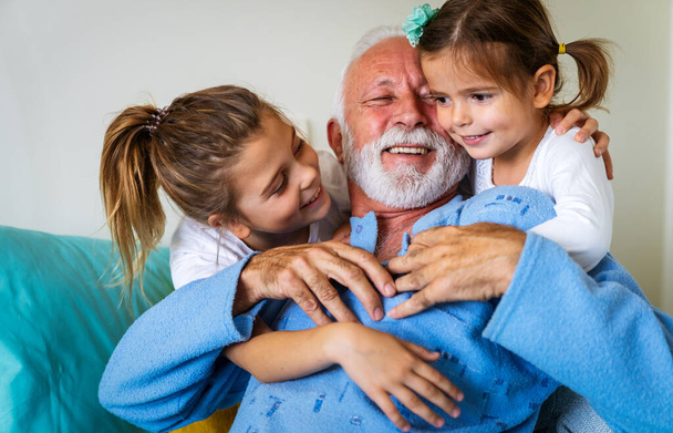 Happy children with senior grandfather laughing and enjoying leisure time together. Family, support, fun concept - Photo, Image