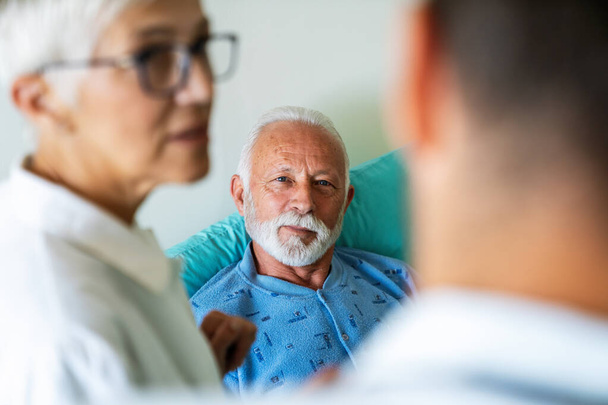 Doctors consulting a mature man patient in hospital. Healthcare people insurance concept - 写真・画像