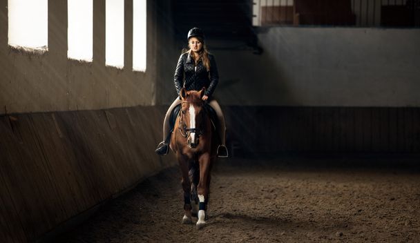 photo de femme équitation cheval sur le manège dans le hall d'équitation
 - Photo, image