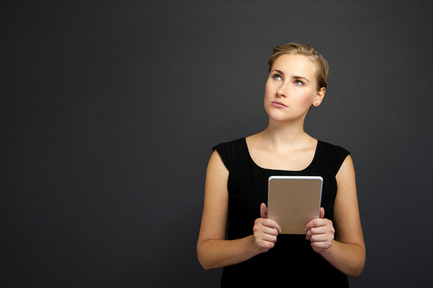 Young woman using a tablet over dark background - Φωτογραφία, εικόνα