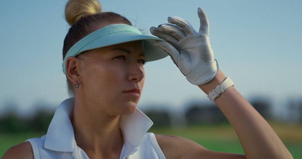 Sporty golf player stand at green course. Portrait of serious woman face look distance outside. Focused golfer check analyzing game result at country club fairway. Recreation luxury lifestyle concept. - Foto, imagen