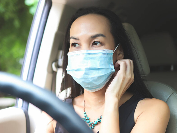 Image rapprochée de la belle femme asiatique portant un masque médical pendant la conduite de la voiture Protection Covid-19 et nouveau concept normal. - Photo, image