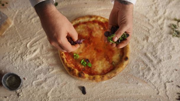 Şef restoranda geleneksel İtalyan pizza tarifini hazırlıyor. Pasta aşçısını kapat ve pizzacıya şifalı bitkiler ekle. Meçhul adam lezzetli bir akşam yemeği pişiriyor. Lezzetli yemek konsepti.. - Fotoğraf, Görsel