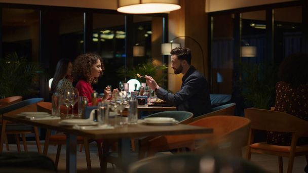 Una pareja de enamorados comiendo juntos en una elegante mesa de restaurante. Dos personas multiétnicas comparten deliciosa comida italiana en la cena romántica. Los amantes pasan tiempo en la celebración del aniversario en la cafetería. Concepto de amor - Foto, Imagen