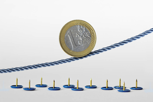 Euro coin on rope over push pins - Concept of upward trend of euro currency and euro currency risk - Photo, Image
