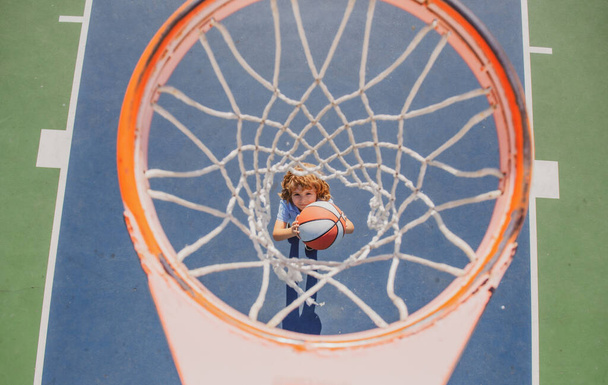 Angle view from on top of child playing basketball on playground - 写真・画像