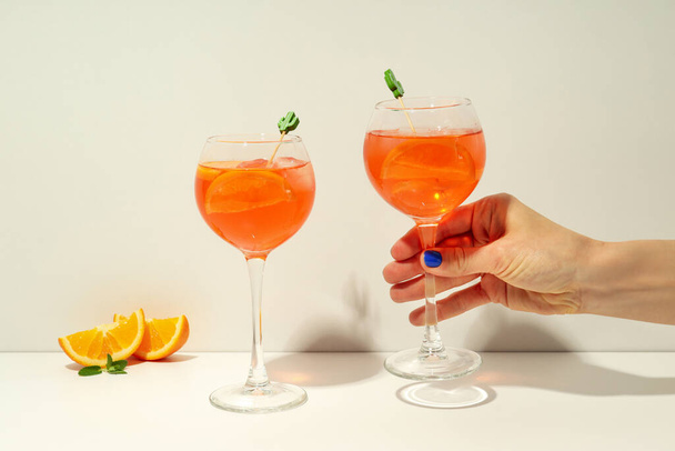 Concept of summer alcohol drink, female hand holds Aperol Spritz - Foto, afbeelding