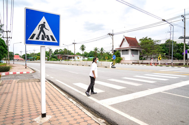 asiático hombre mira a vehículo en el camino, él espera seguro a través de paso de peatones al otro lado, Tailandia. - Foto, imagen