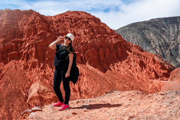 Młoda kobieta pozowała w Purmamarce, Jujuy, Argentynie. Kobieta pozująca na szczycie wzgórza. Północna Argentyna. Czerwona ziemia - Zdjęcie, obraz