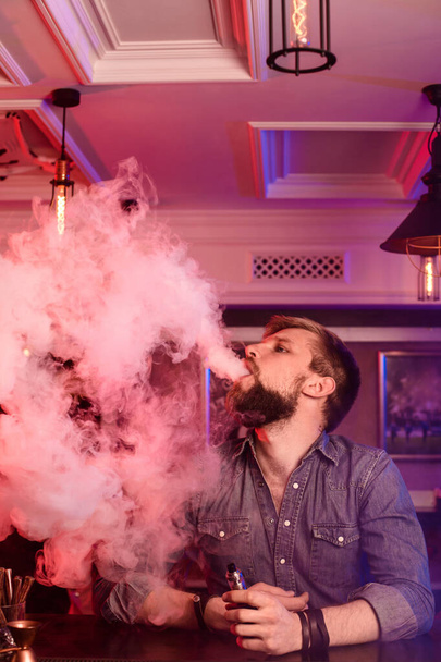 Vape. Buhar bulutu içindeki bir adamı buharlaştırmak. Fotoğraf bir vape barda çekilir. Vestiyer. - Fotoğraf, Görsel