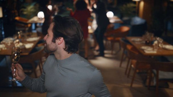 Веселый парень танцует на новогодней вечеринке. Красивый мужчина любит петь караоке в ресторане кафе. Молодой человек, держащий бокал шампанского на крутой встрече друзей. Развлекательная концепция. - Фото, изображение