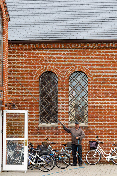 Skagen, Dania Człowiek myje okna w kościele Skagen kirke lub Skagen. - Zdjęcie, obraz