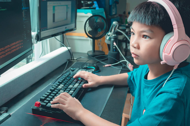 Asiatico bambino è codifica e scripting programma sul suo gioco streaming desktop computer con cuffie su. - Foto, immagini
