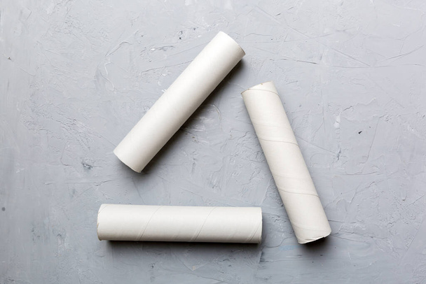 Rollo de papel higiénico vacío sobre fondo de color. Tubo de papel reciclable con extremo de tapón metálico hecho de papel kraft o cartón en forma de signo de reciclado. - Foto, imagen