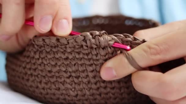 ピンクのフックとラフィア糸で装飾的な茶色のバスケットをクロッキー編んだ女性の手のフロントビューを閉じます。天然素材、趣味から手作りアクセサリーの作成。高品質4k映像. - 映像、動画