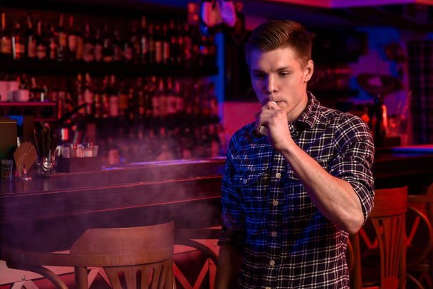 The man smoke an electronic cigarette at the vape shop. Vape bar. - Fotografie, Obrázek