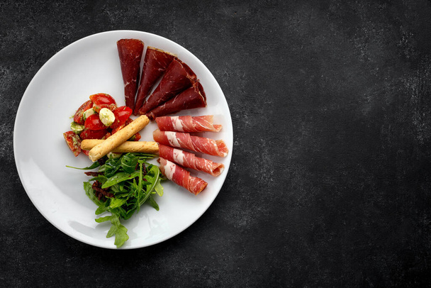 Закуска из мяса с овощным салатом, рукколой и гриссини - Фото, изображение
