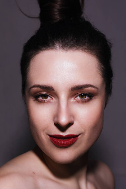 Portret van een vrouw met elegante, gedurfde avondmake-up met luxe donkerrode lippen die zachtjes glimlacht - Foto, afbeelding