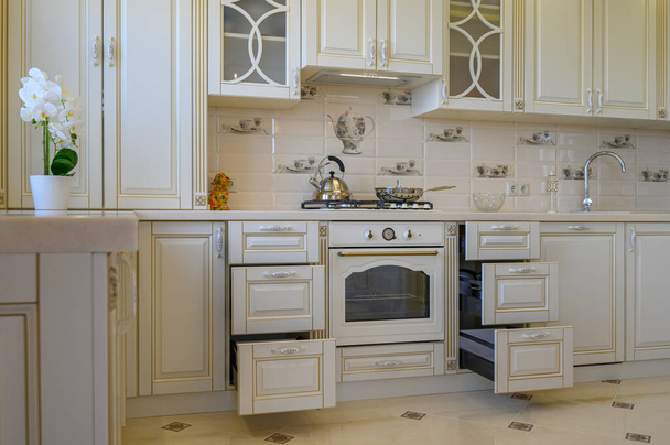 Muebles de cocina clásicos blancos y beige con cajones retraídos en apartamento estudio - Foto, Imagen