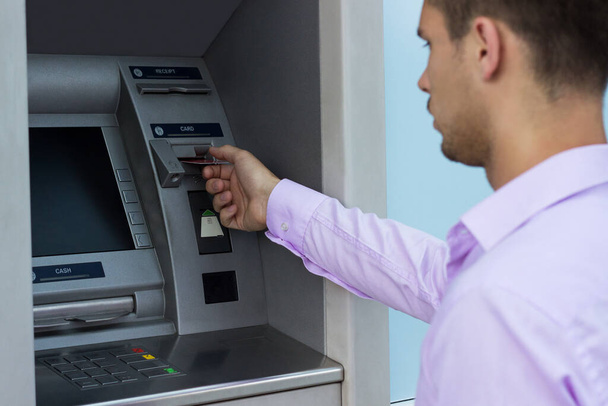 Молодой бизнесмен снимает деньги с банкомата - Фото, изображение