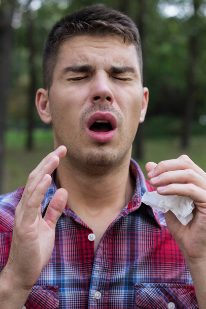 Un giovane con un'allergia starnutisce nel fazzoletto - Foto, immagini