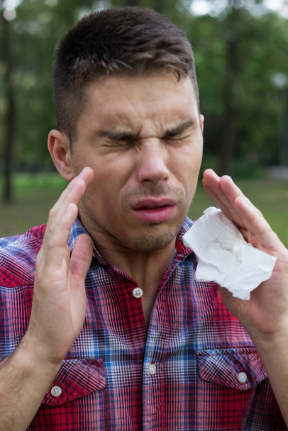 Un giovane con un'allergia starnutisce nel fazzoletto - Foto, immagini