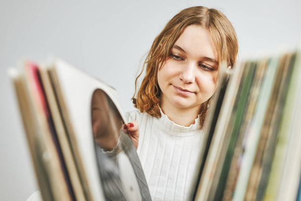 Playing vinyl records. Listening to music from vinyl record player. Retro and vintage music style. Young woman searching analog LP record album in stack of old records. Music collection. Music passion - Fotoğraf, Görsel