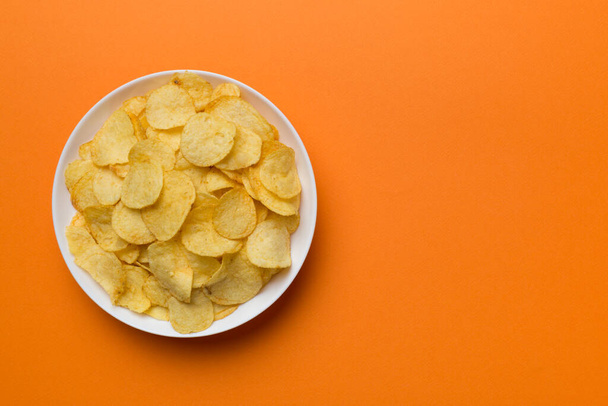 Potato chips on bowl isolated on colored background. Delicious crispy potato chips in bowl. Space for text. Top view. - Φωτογραφία, εικόνα