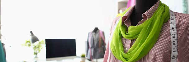 Close-up of mannequin with unique combination of red shirt and green scarf. Creative workspace in cozy small studio. Small family business, atelier concept - Photo, Image